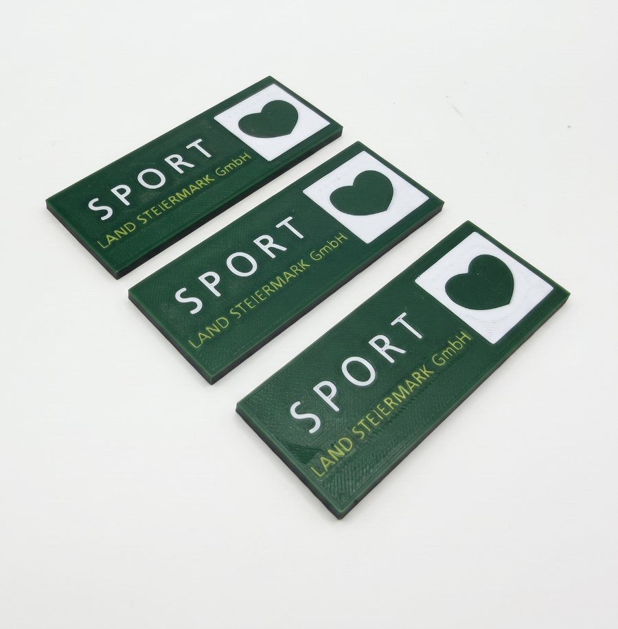Drei Logo-Plaketten der Sport Land Steiermark GmbH, mehrfarbig gedruckt in Grün, Weiß und Hellgrün